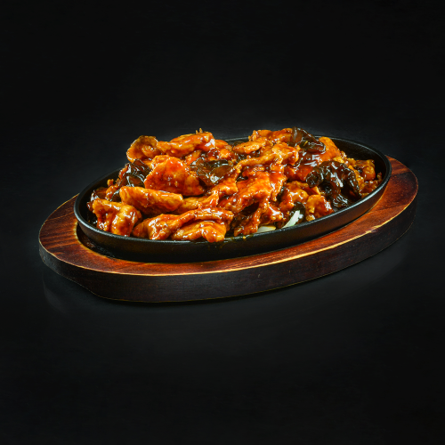 Pork with black mushrooms in sweet and sour spicy sauce in a pan